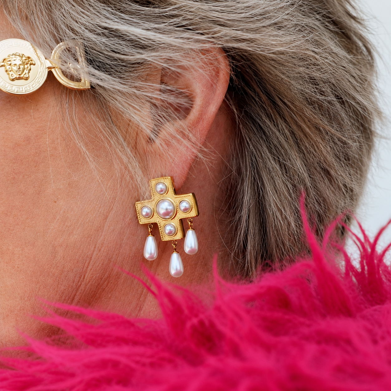 Model wearing the Pearls Before Drama gold cross drop earring with cubic zirconia and faux-pearl drops