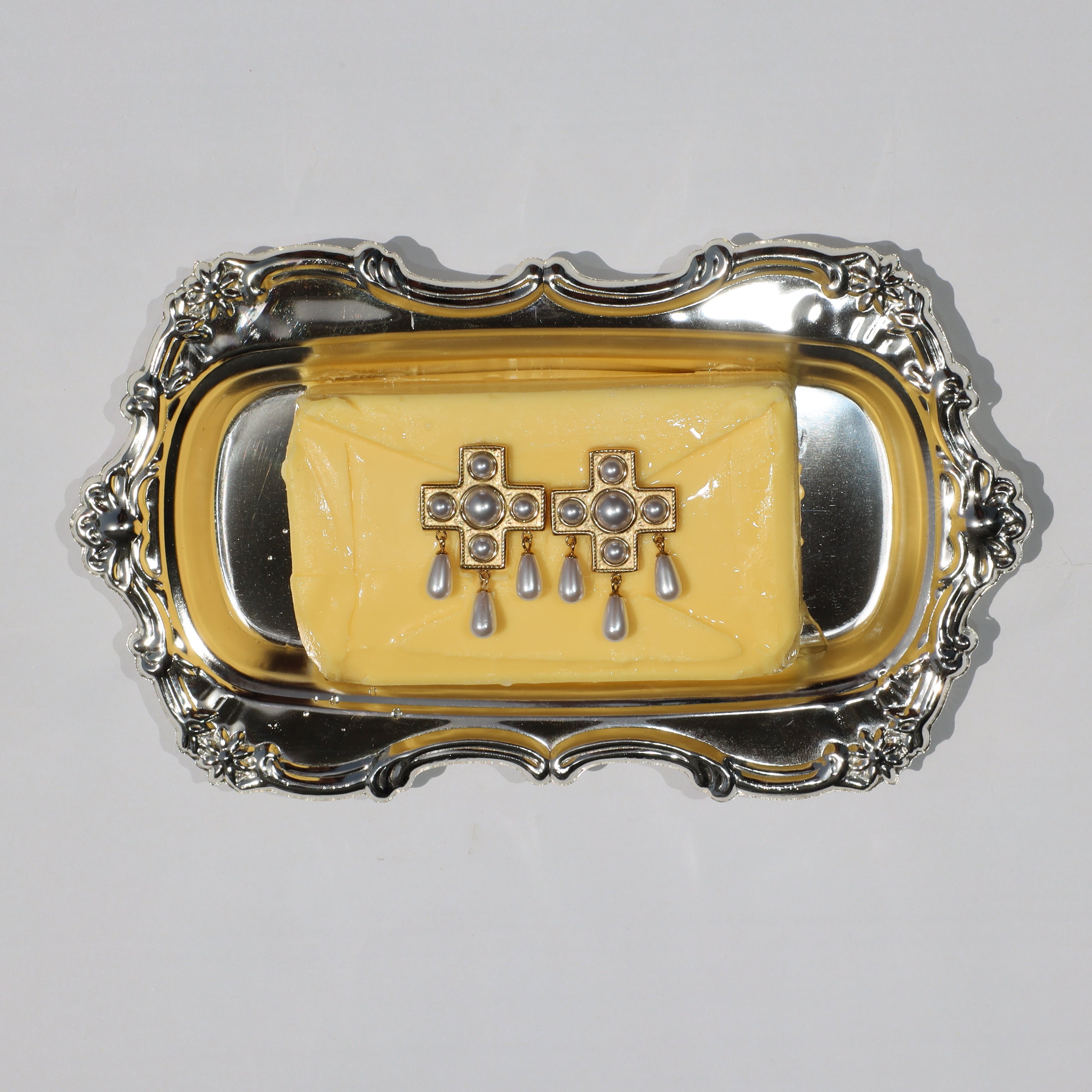 Pair of Pearls Before Drama gold cross drop earrings with cubic zirconia and faux-pearl drops, displayed on a silver tray