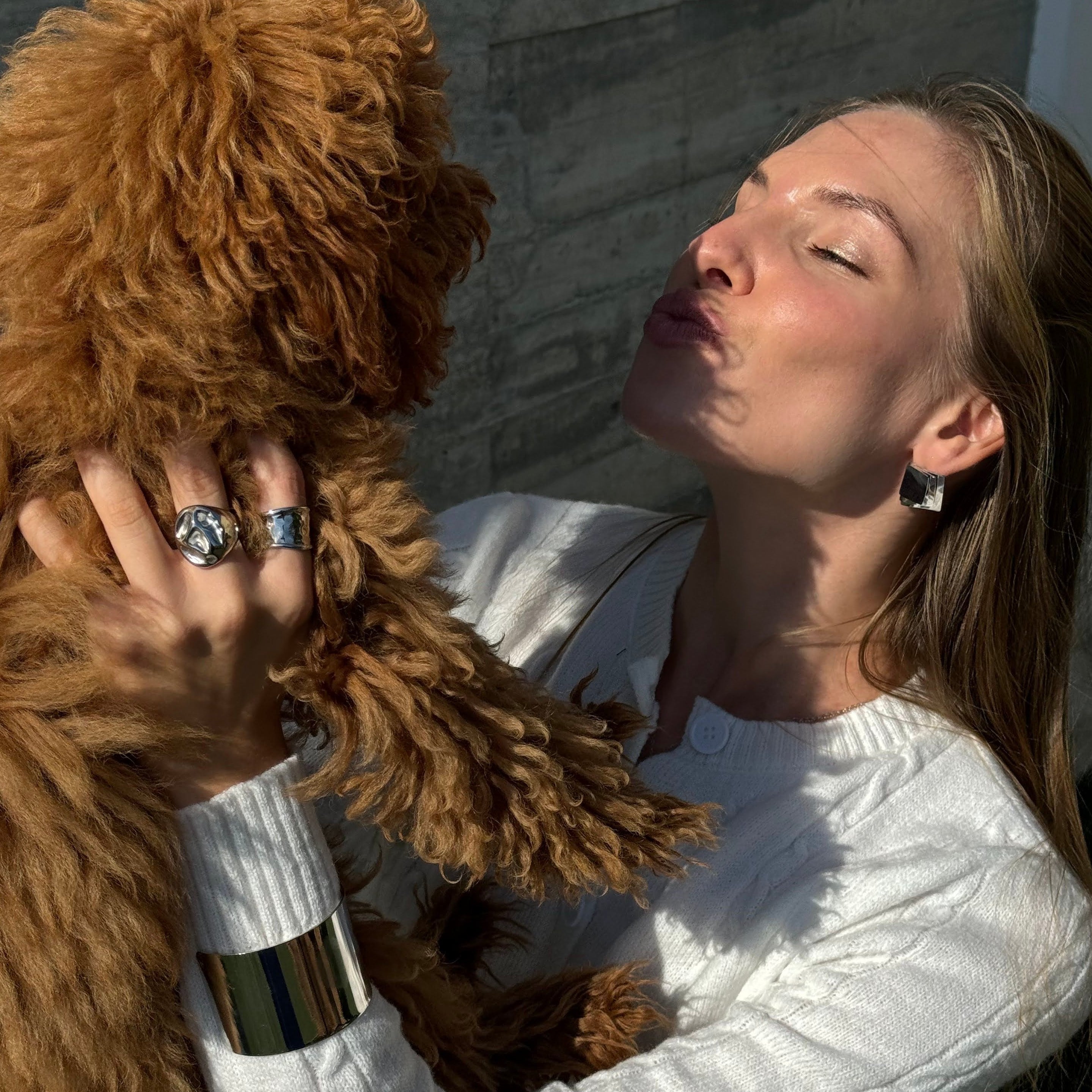 Model wearing the irregular bold chunky ring in PVD-coated 925 silver-plated stainless steel while holding a small brown dog