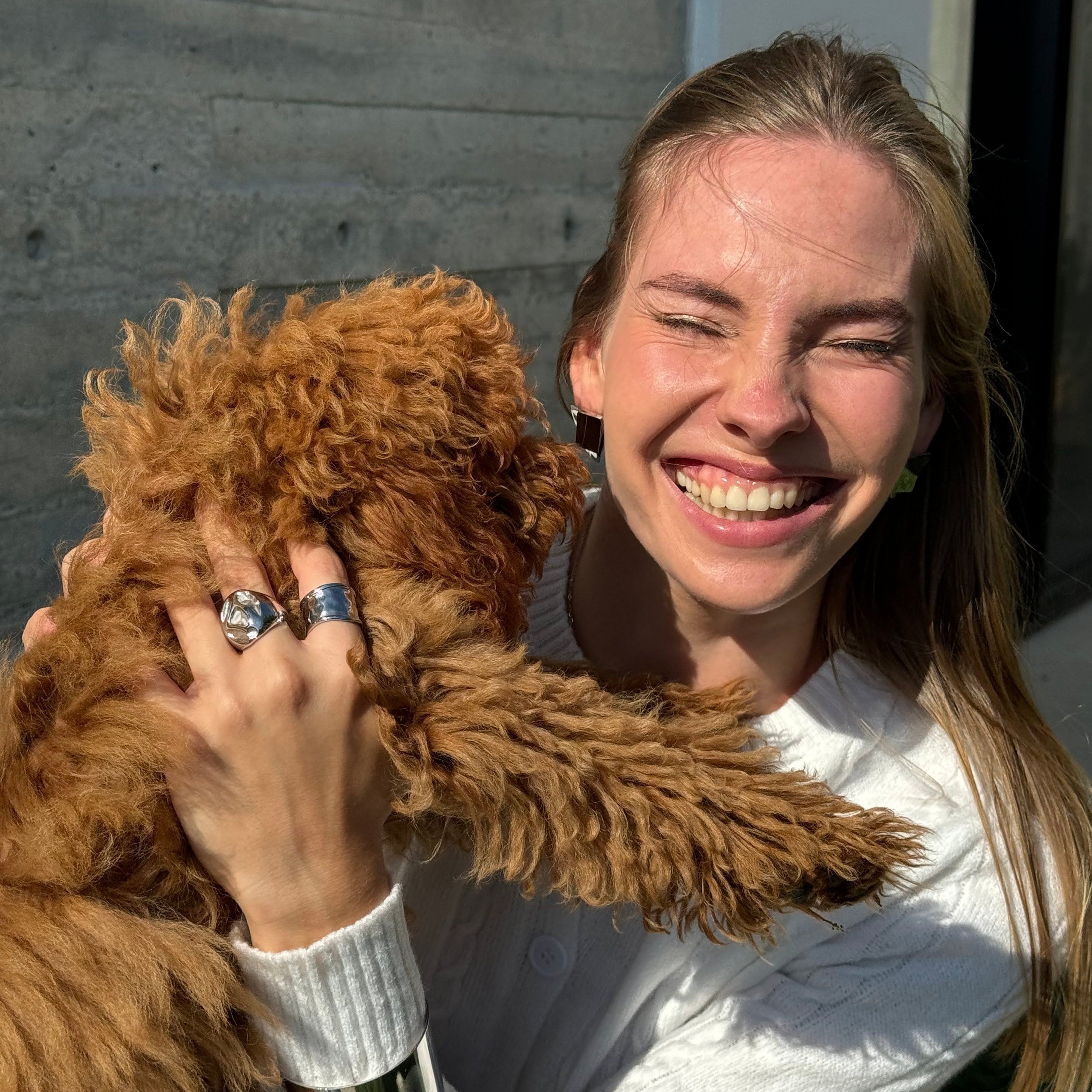 Smiling model wearing the irregular bold chunky ring in PVD-coated 925 silver-plated stainless steel while holding a brown dog