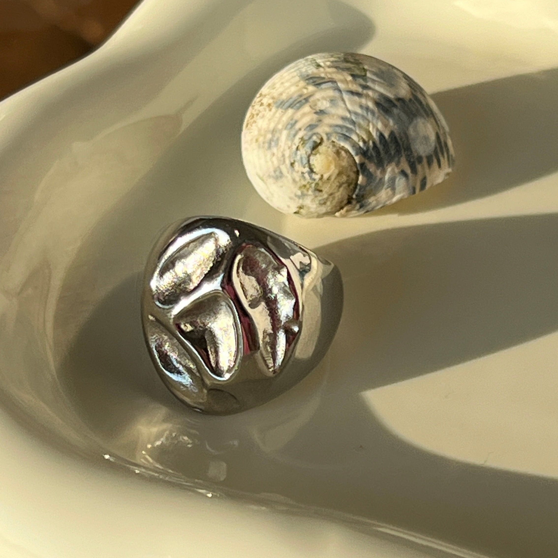 Irregular bold chunky ring in PVD-coated 925 silver-plated stainless steel displayed on a white dish
