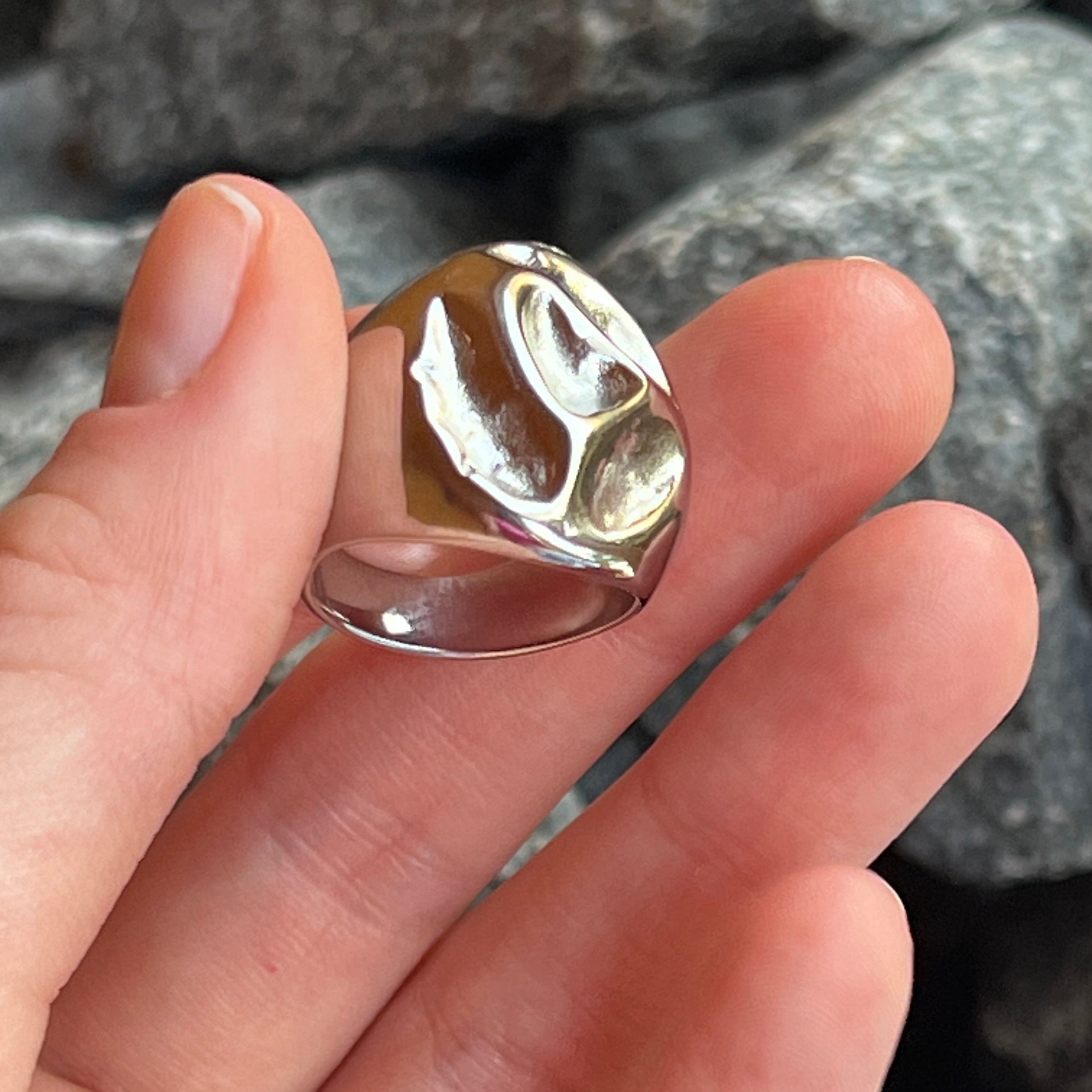 Hand holding the irregular bold chunky ring in PVD-coated 925 silver-plated stainless steel against a stone background