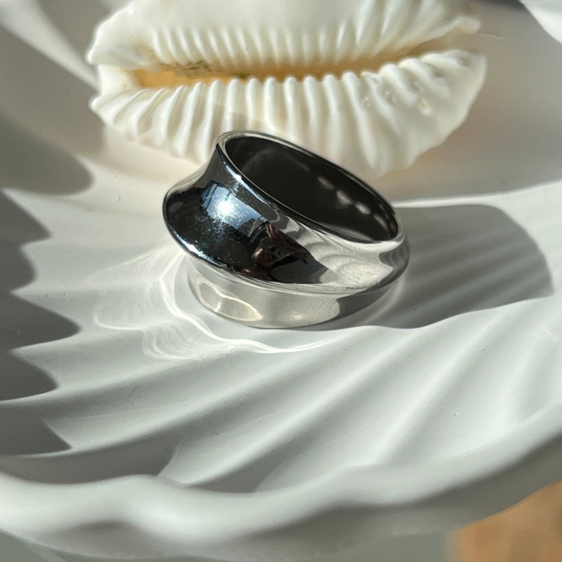 Fashionable dome ring in PVD-coated 925 silver-plated stainless steel displayed on a white textured dish