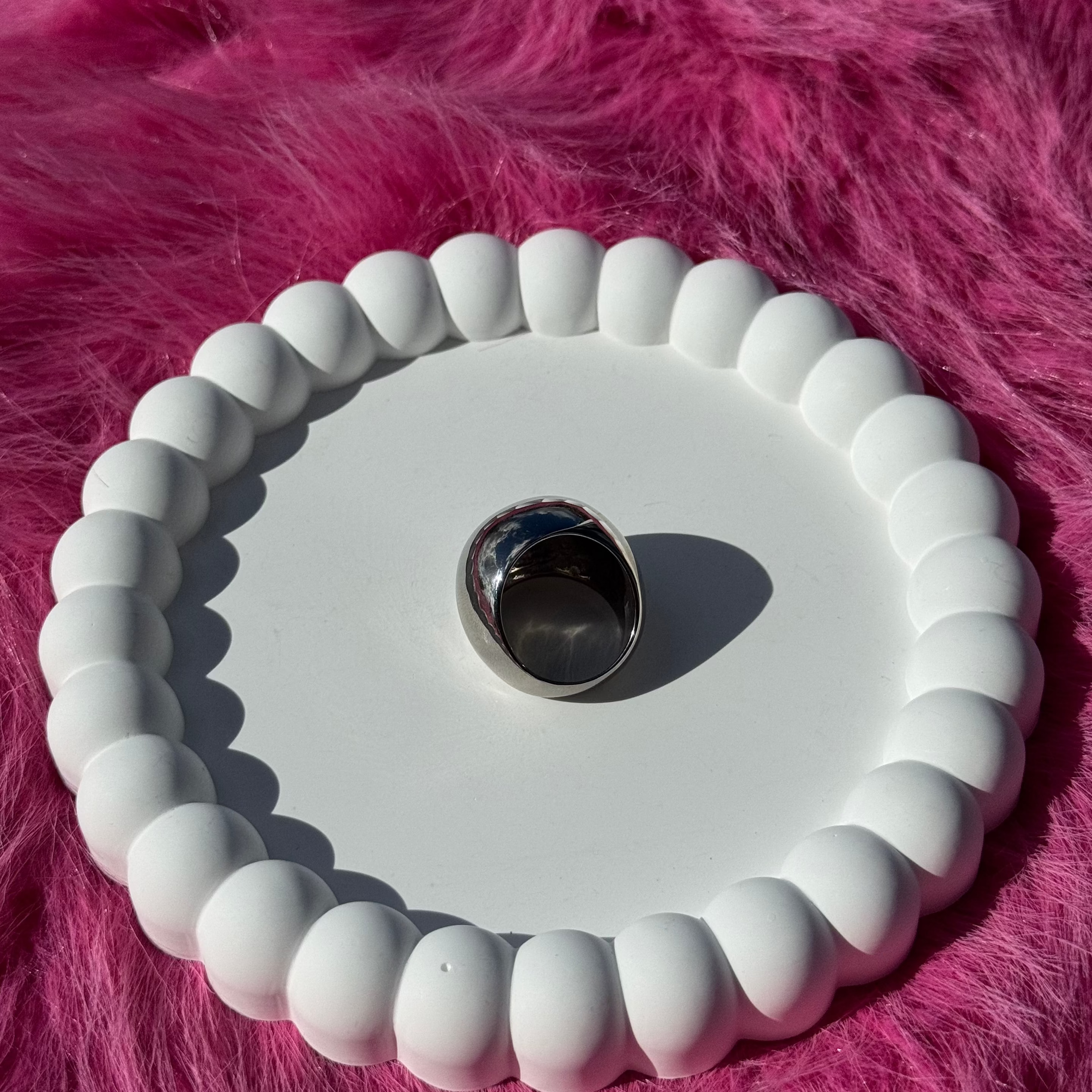 Top view of the ball ring in PVD-coated 925 silver-plated stainless steel on a white beaded dish against a pink fur background
